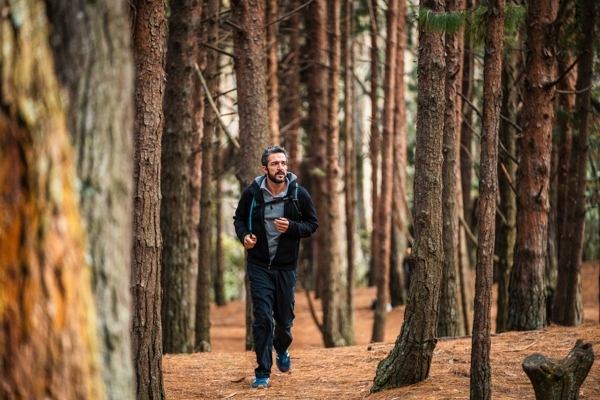 Sendero Quebrada La Vieja hombre en sudadera trota alrededor de los árboles.