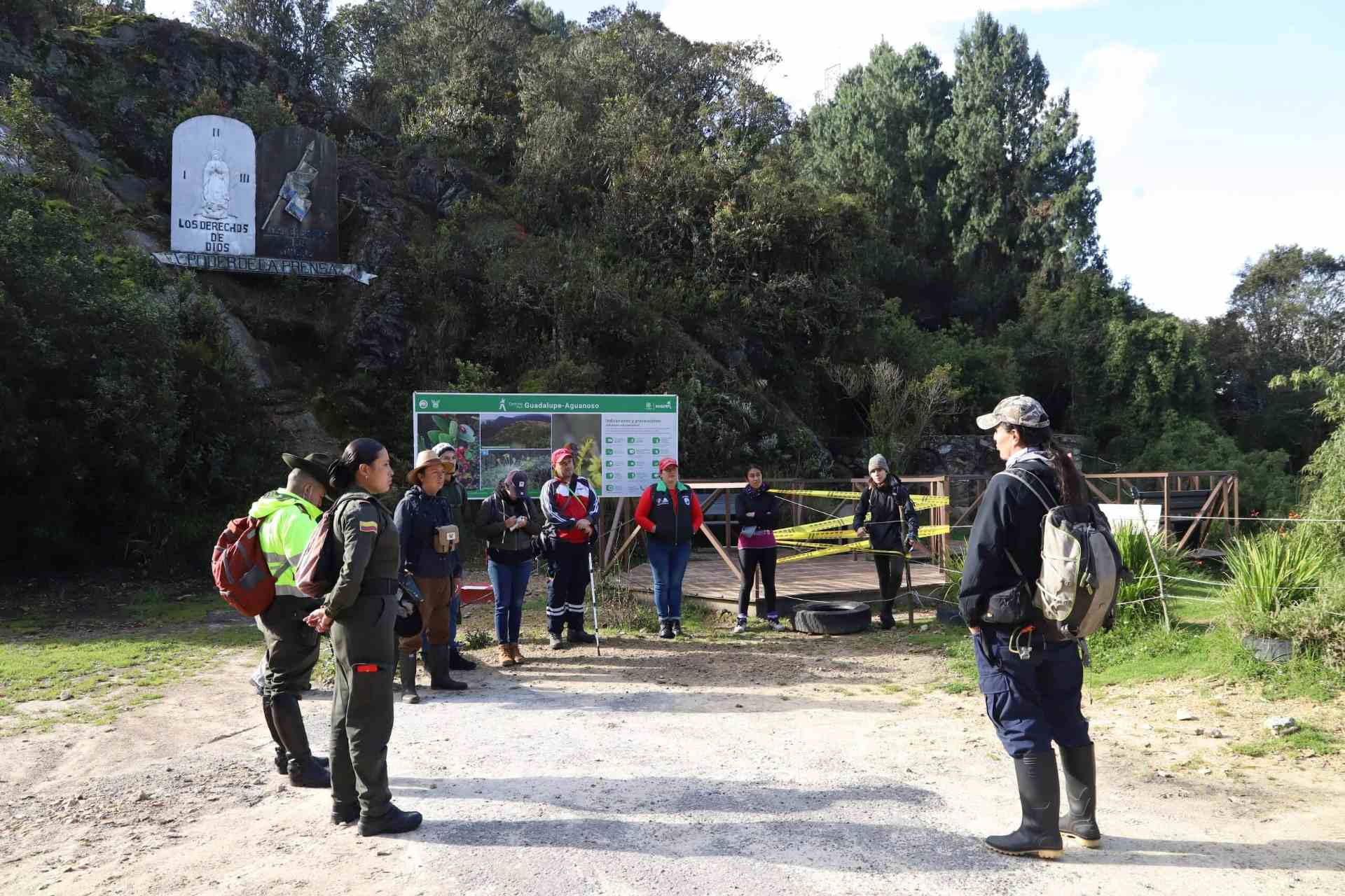 Guia turístico da orientaciones a grupo de visitantes que hacen el camino por el sendero Guadalupe - Aguanoso. Dos agentes de policía observan.