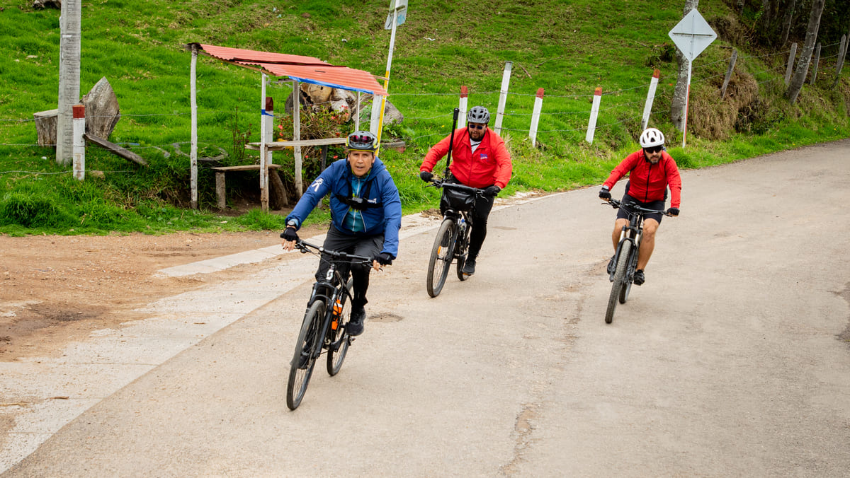 Tres ciclistas pedalean en caminos rurales.
