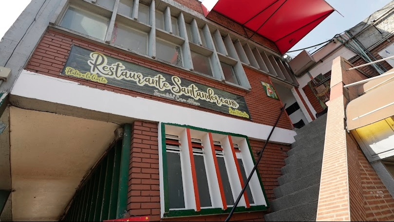 Fachada de un local comercial en donde hay un aviso que dice "Restaurante Santandereano". Hay una alta escalera que conduce a un segundo piso