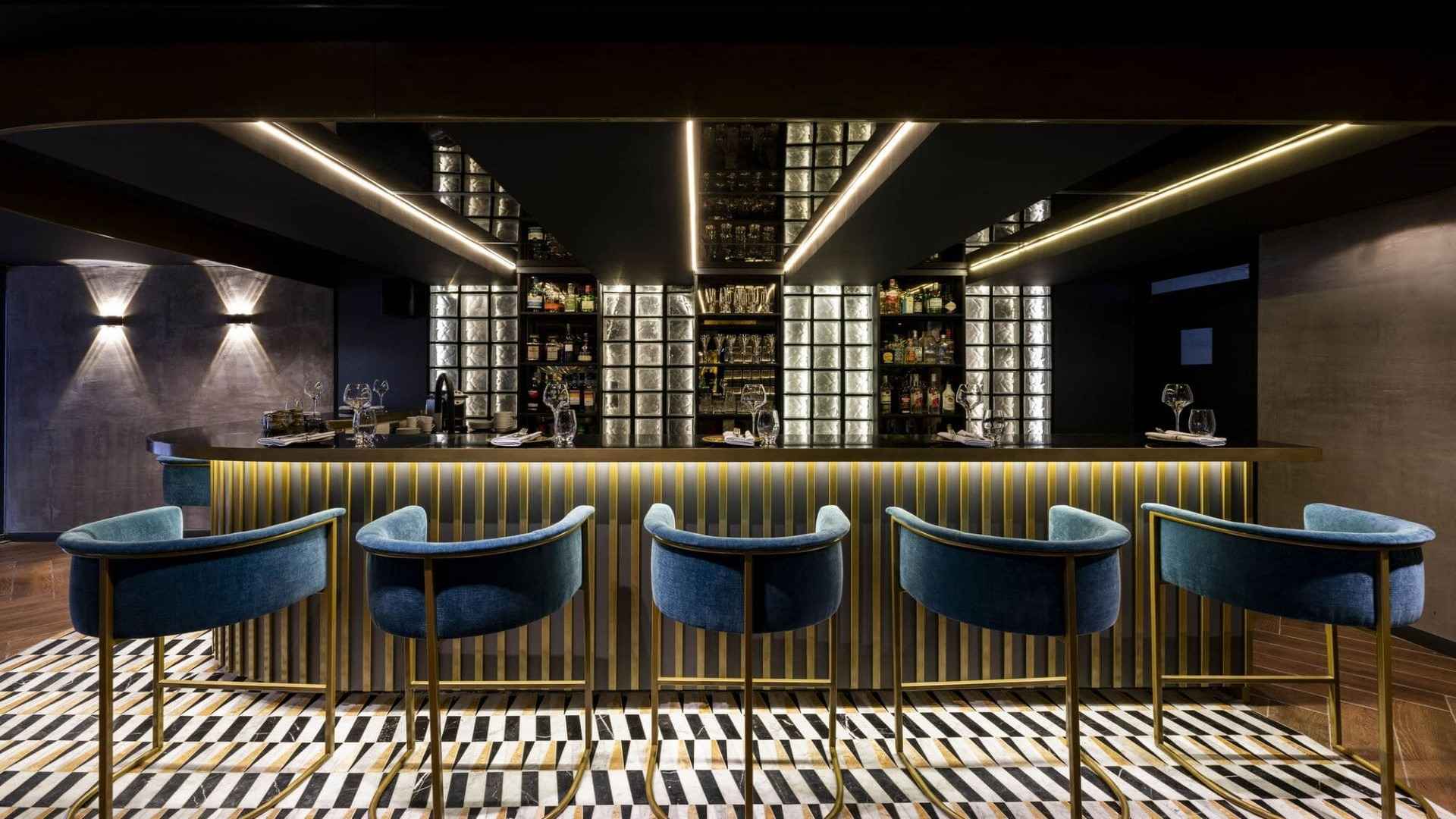 Diseño sobrio y elegante en la barra. Los taburetes azules y el ambiente tenue invitan a una copa. 