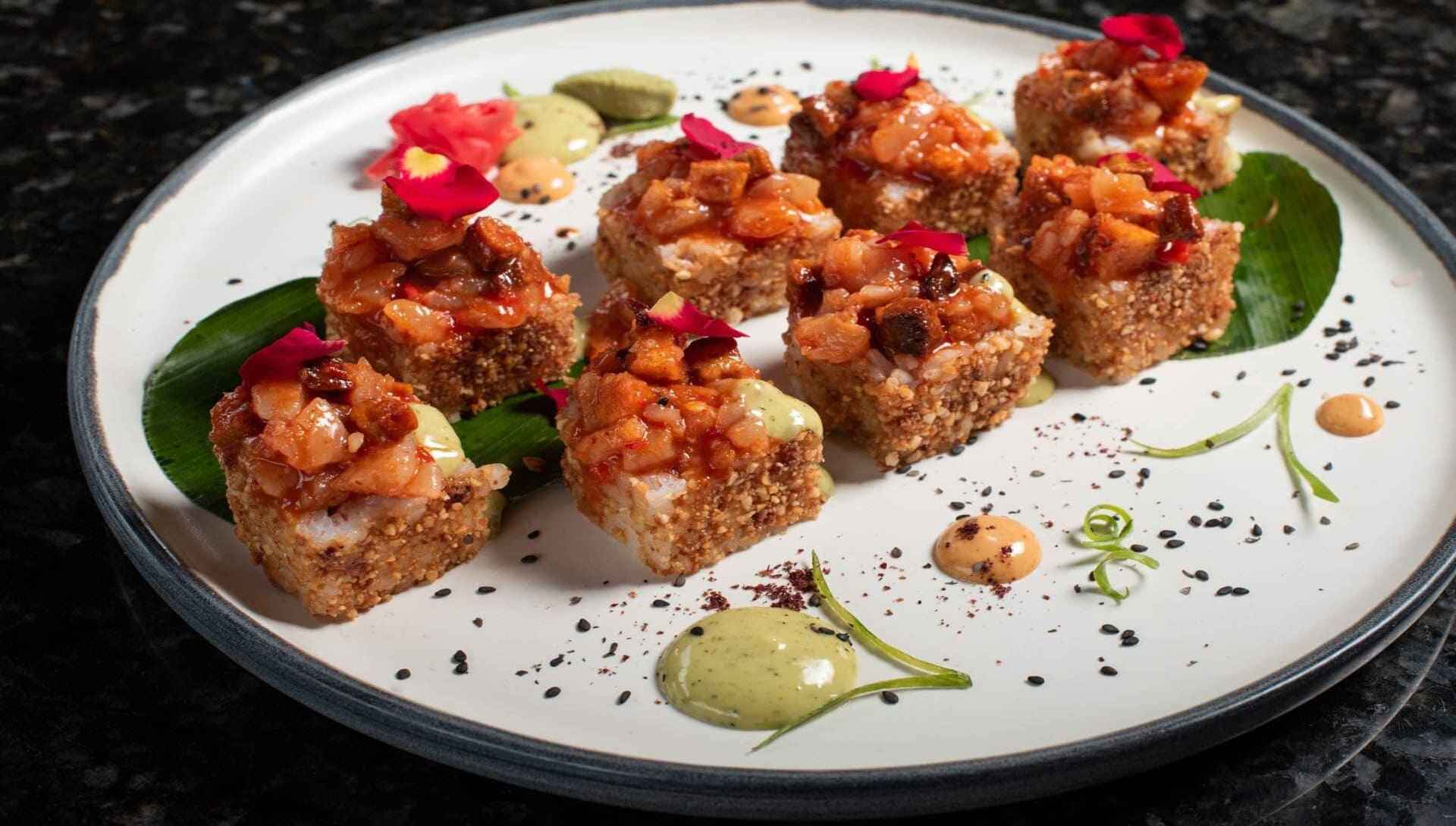 Interior de un restaurante con lámparas colgantes, figuras de peces y paneles de madera verticales.