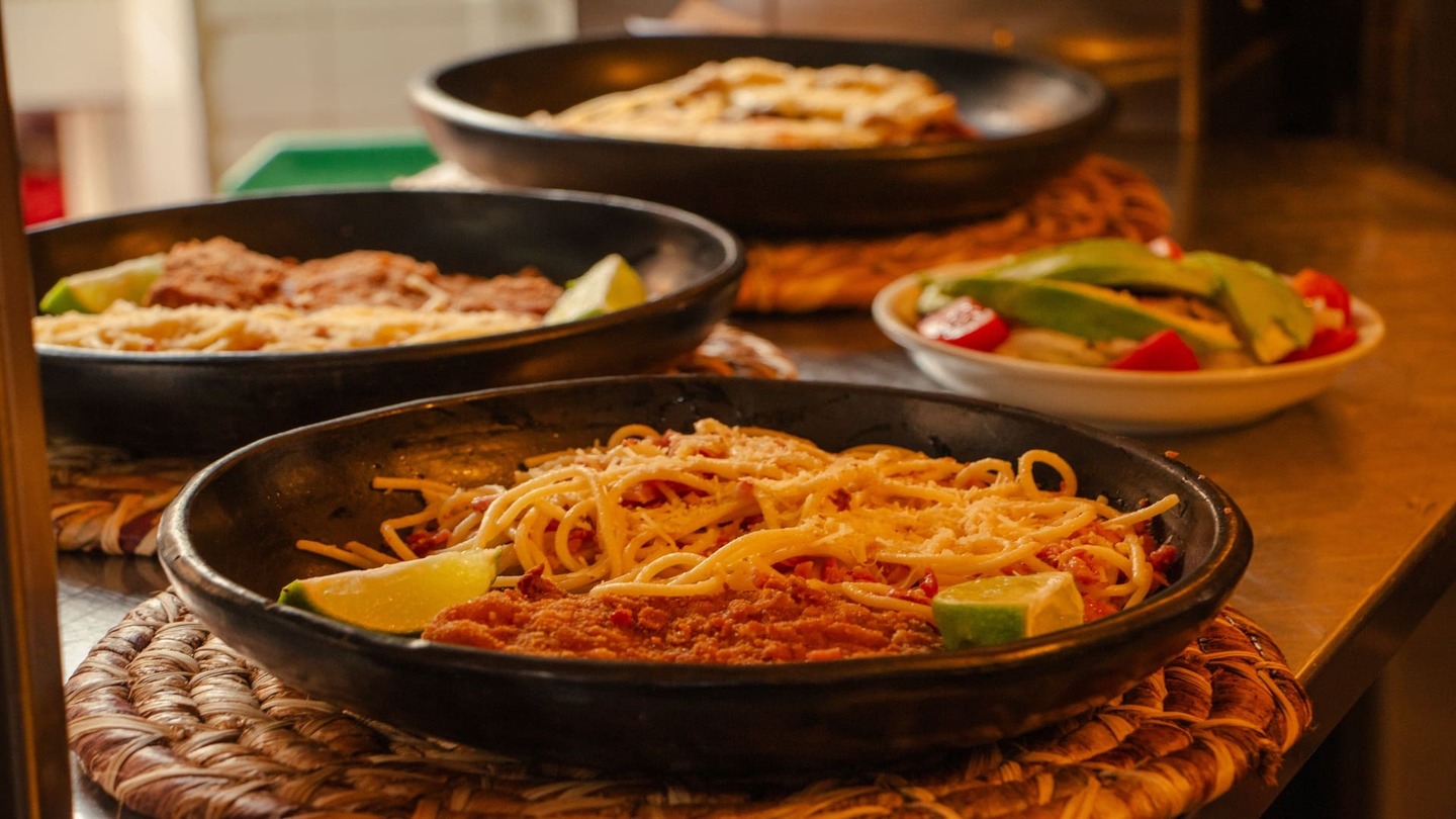Tres platos de pasta con queso y limón, acompañados de una ensalada fresca, listos para servir.