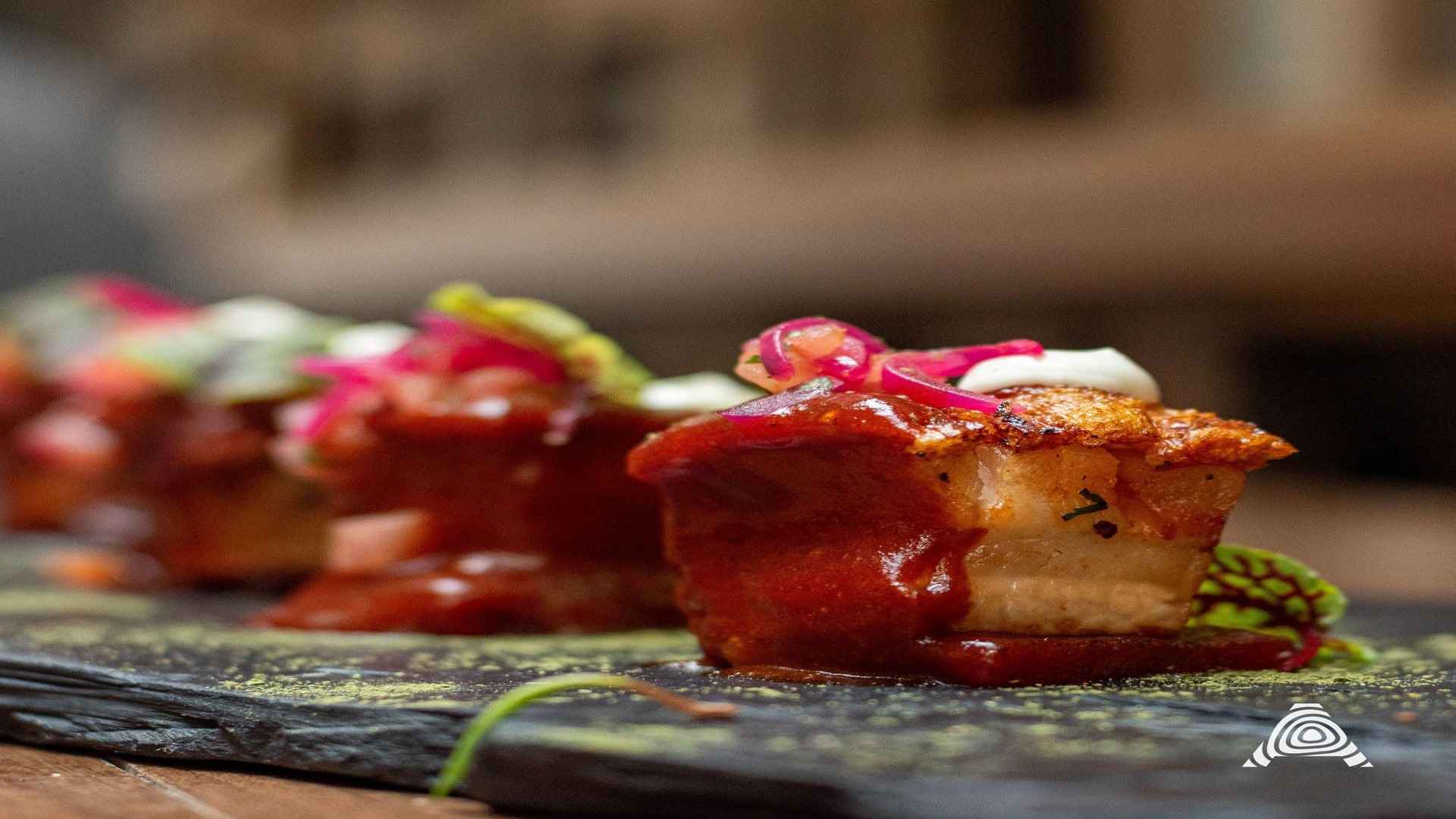Suculentos trozos de carne con una costra crujiente, bañados en una rica salsa roja y adornados con cebolla encurtida.