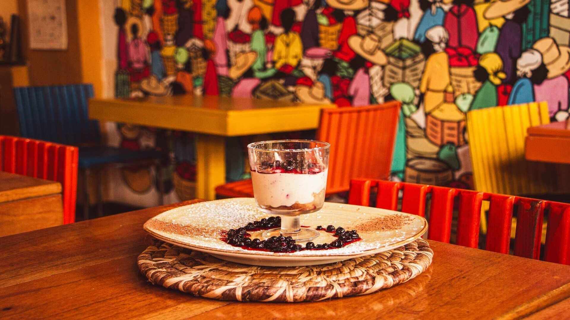 Un postre de capas con salsa de frutos rojos, servido en un plato decorado sobre una mesa de madera.