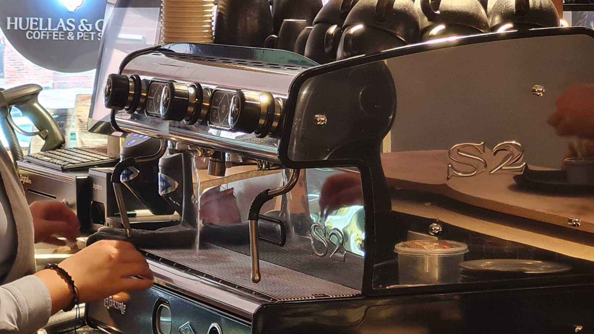 Un barista preparando café en una máquina espresso profesional de acero inoxidable, con atención al detalle.