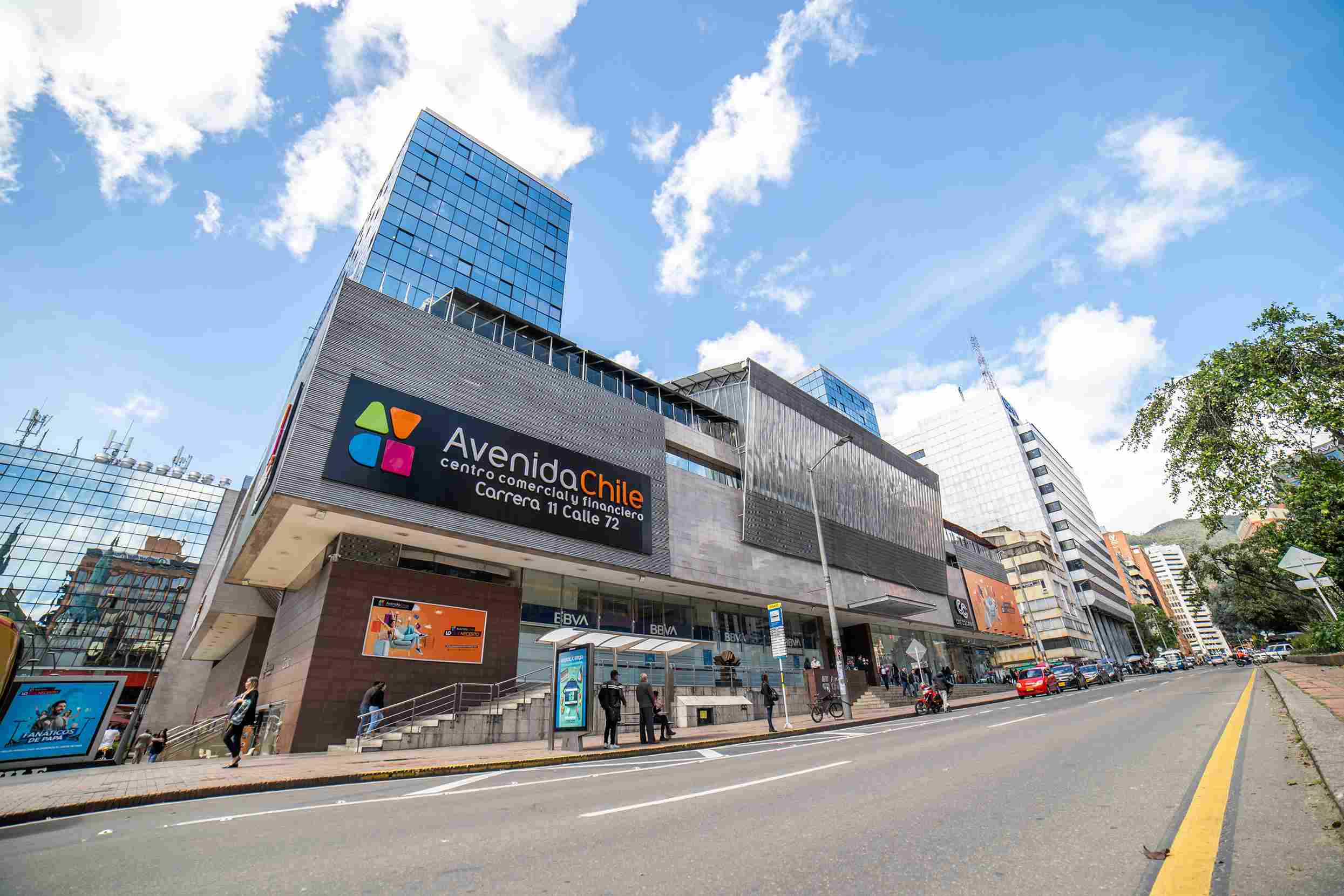 Fachada del Centro Comercial Avenida Chile, en baldosa gris y vidrio. Al frente hay una avenida sin carros. Hay detrás unos edificios altos en vidrio.
