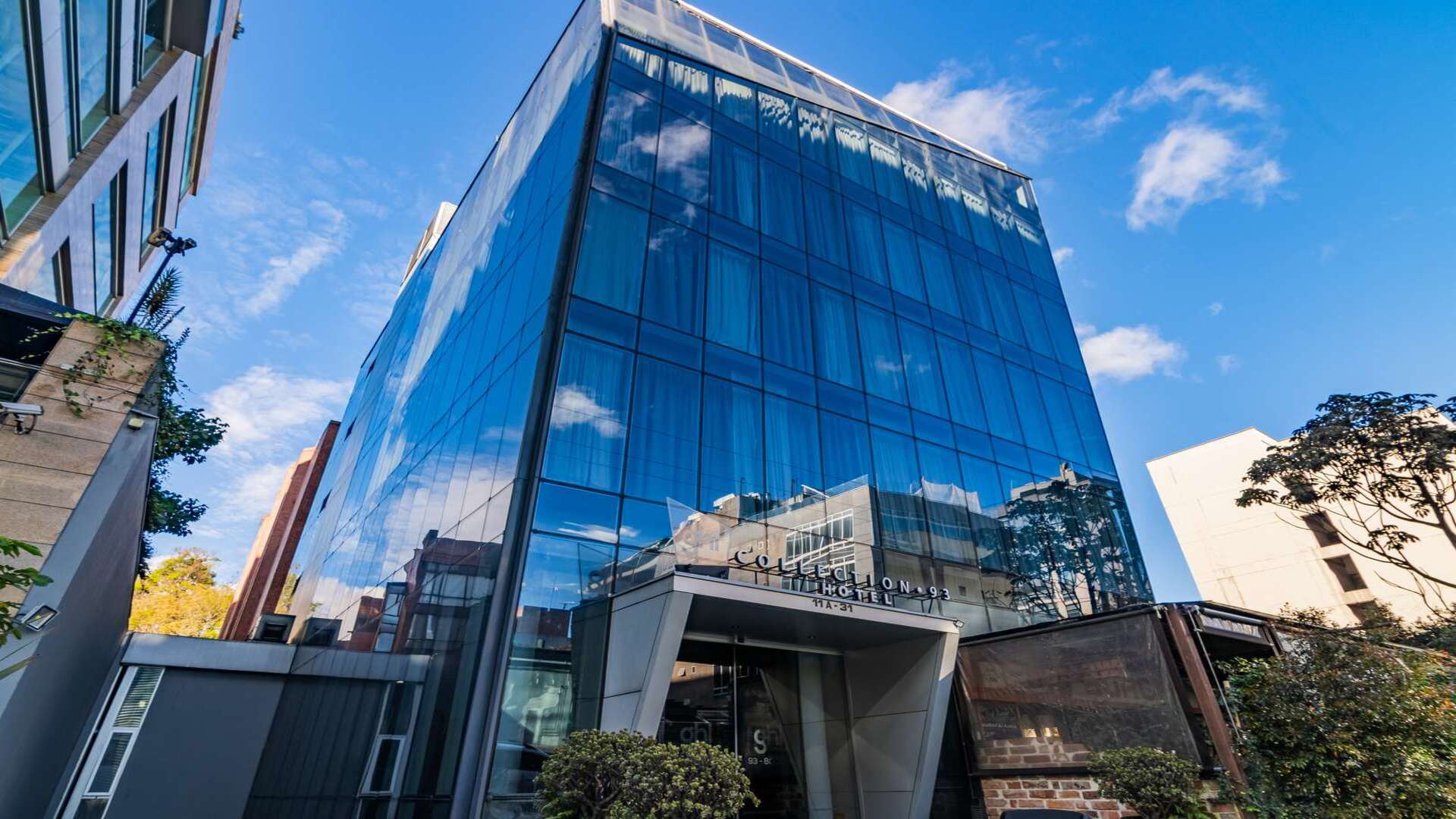 Moderno hotel de cristal "Collection 93" con reflejos del cielo.