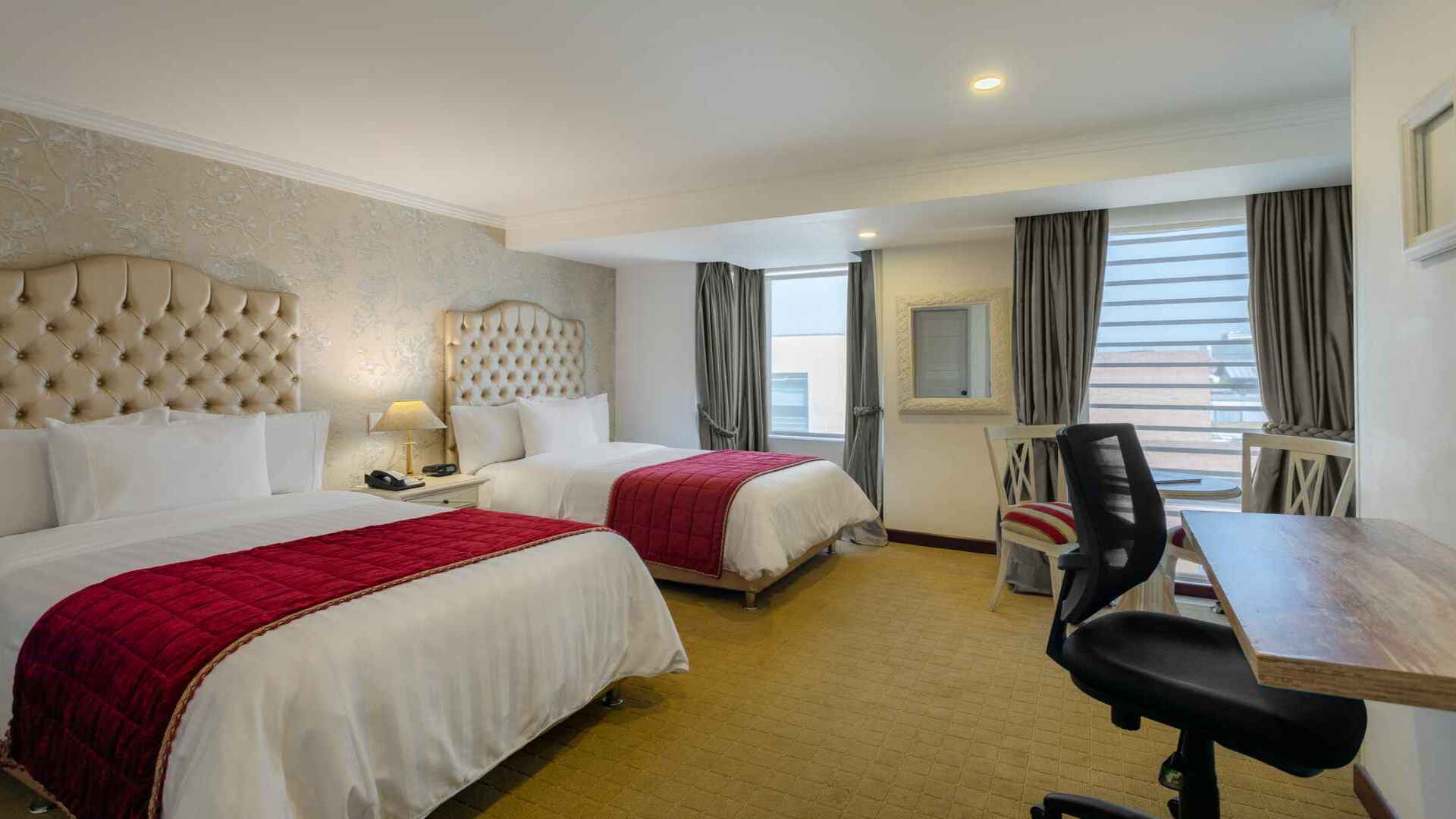 Habitación de hotel con dos camas dobles y escritorio. 