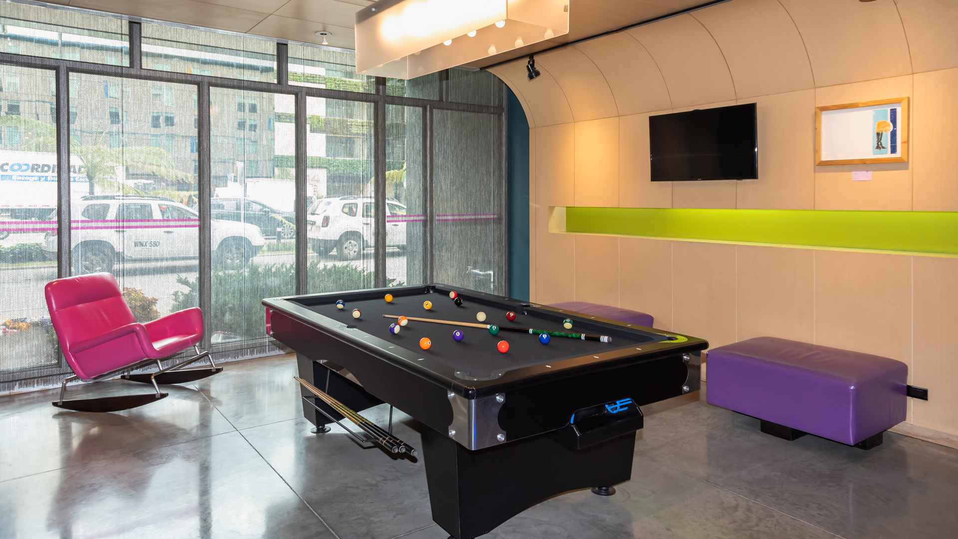 Una sala de juegos relajada con una mesa de billar, sillones de colores y un ambiente casual, ideal para el entretenimiento.