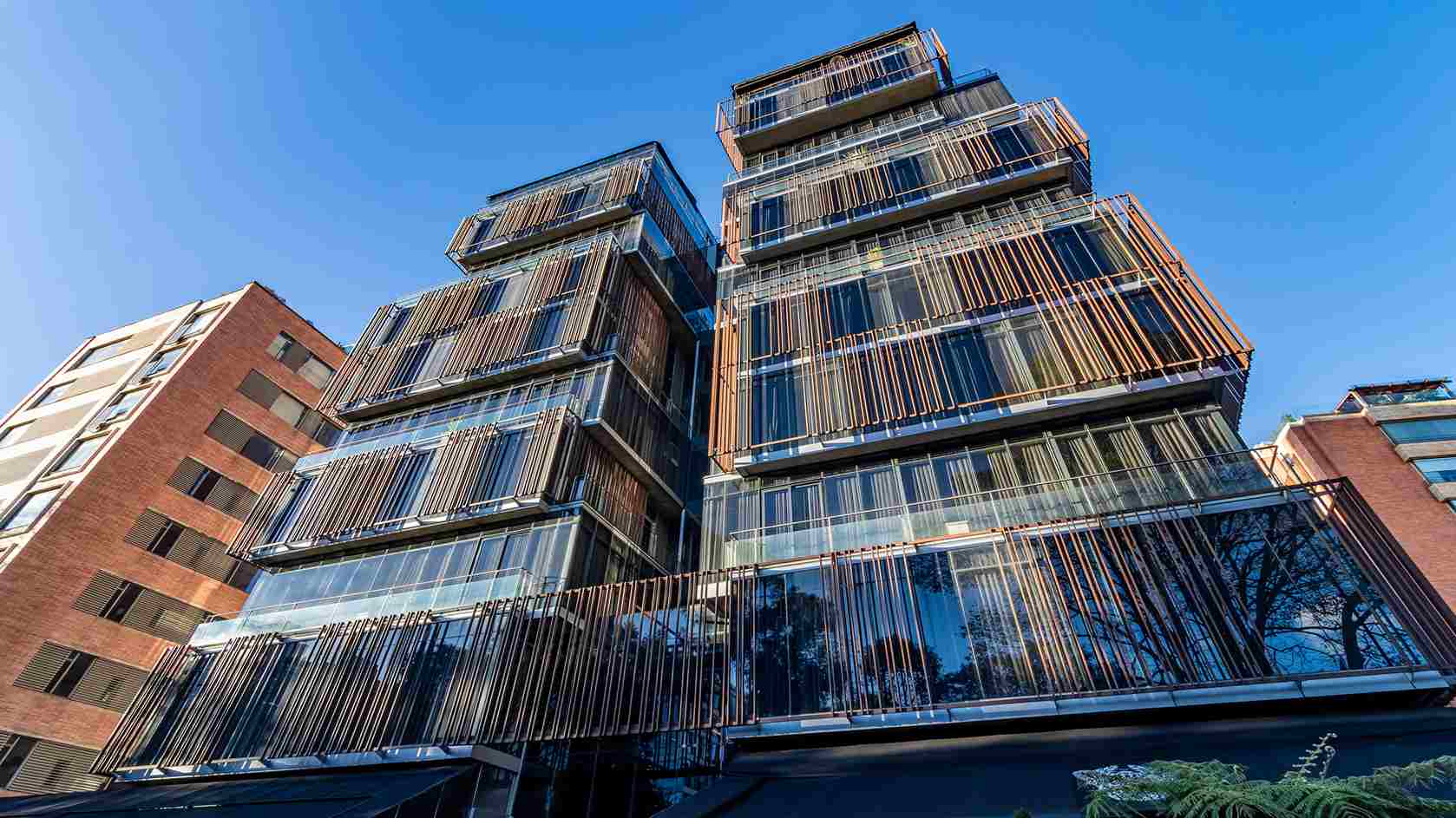 Un edificio moderno con una fachada distintiva de paneles verticales y grandes ventanales. La arquitectura es contemporánea y elegante.