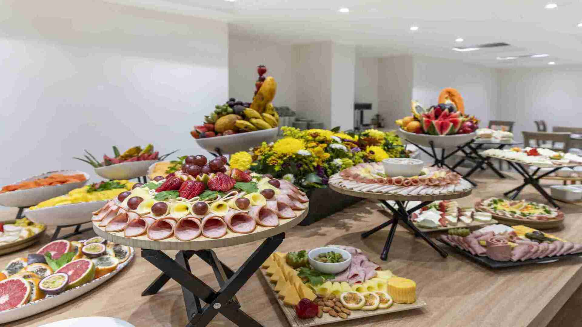  Una mesa de buffet con una abundancia de frutas frescas, embutidos, quesos y otros bocadillos, presentados de forma artística y apetitosa.