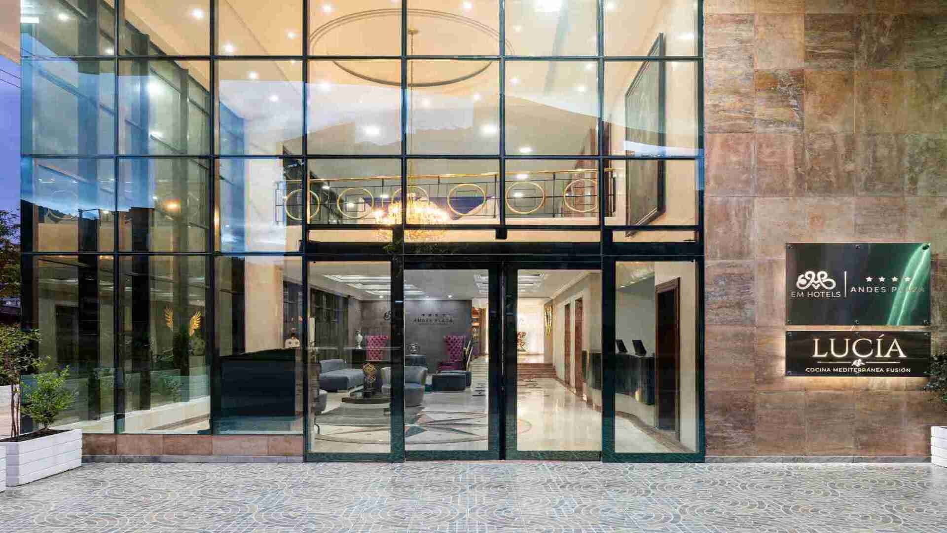 La entrada principal del Hotel Andes Plaza y del restaurante Lucía, con una fachada de cristal imponente y un letrero que indica "Cocina Mediterránea Fusión".