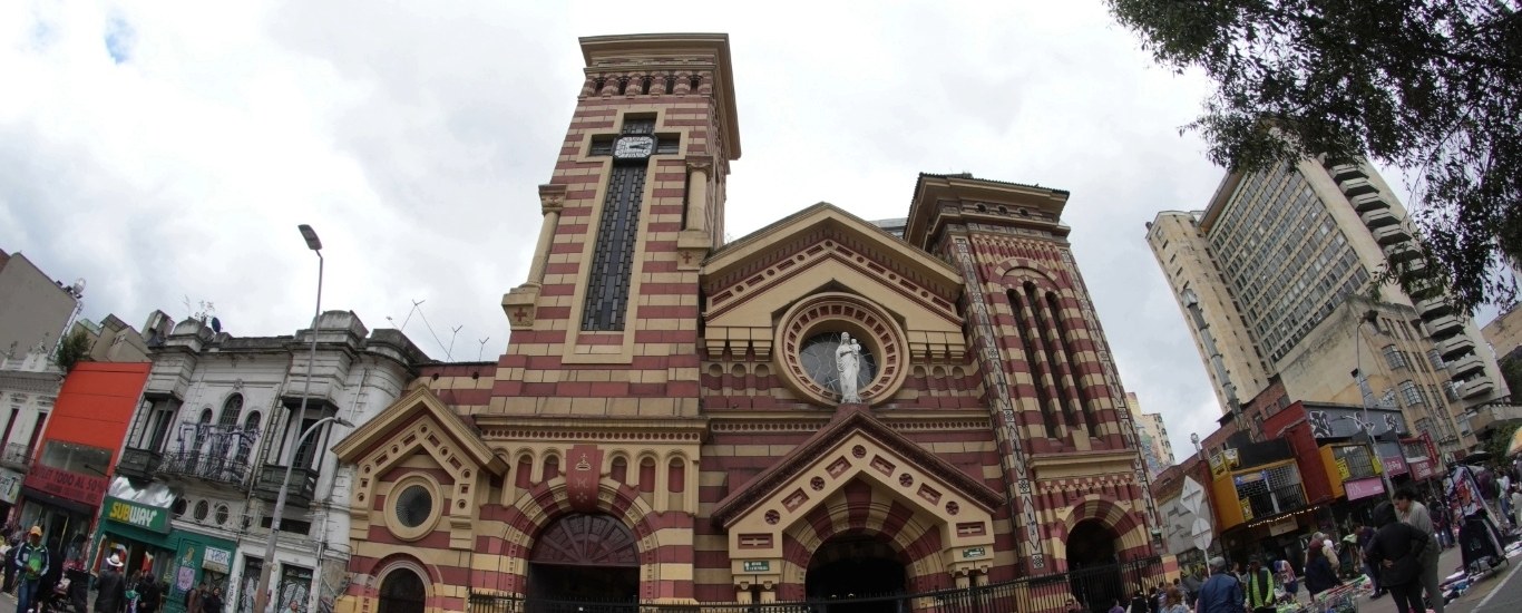 Iglesia de Las Nieves fachada de día cielo gris. Foco angular de iglesia de rayas rojas y amarillas de estilo bizantino, rodeada por edificios de comercio antiguos. A los lados personas caminando.