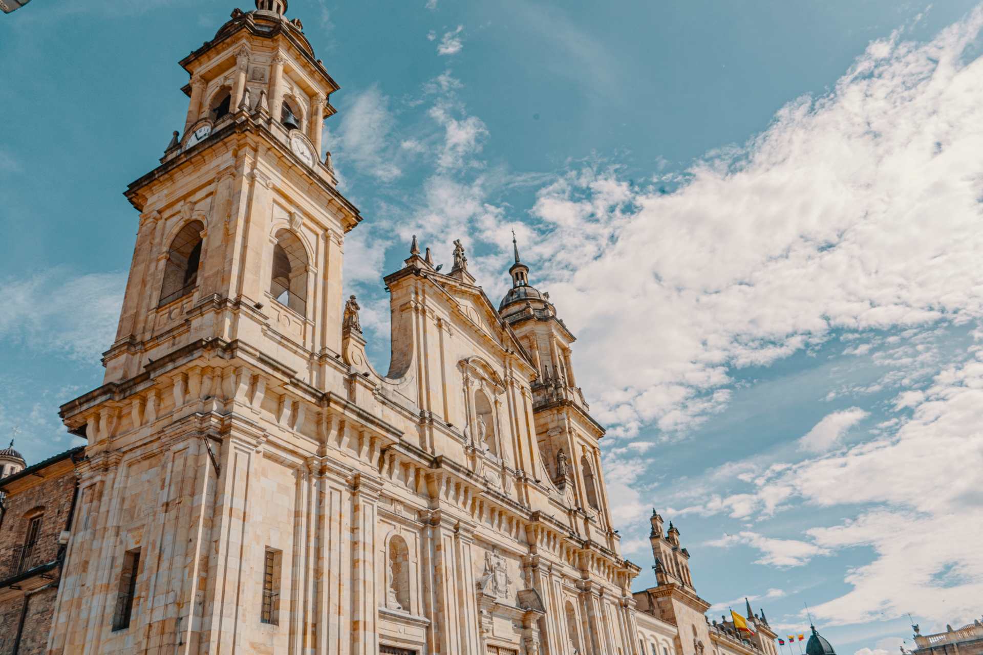 Catedral Primada de Colombia fachada lateral hacia arriba se observan campanarios y torre del reloj. El cielo es azul.