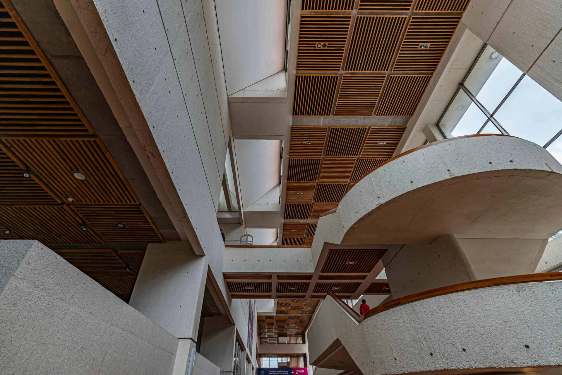 Biblioteca Julio Mario Santo Domingo interior paredes blancas con escaleras en espiral blanco y techos en cuadros de madera. 