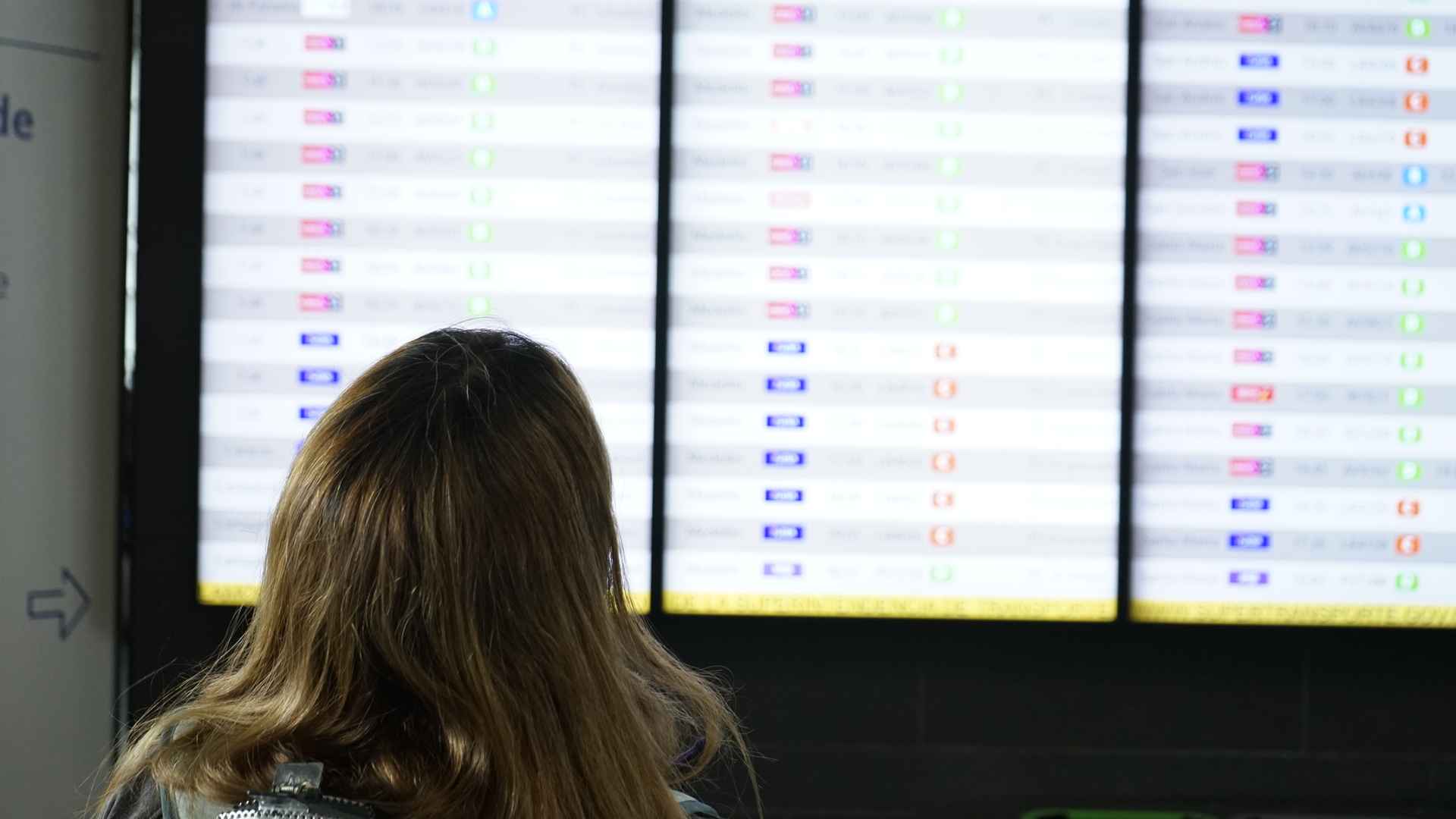 Pasajero consulta las pantallas de salidas para ubicar su sala de abordaje y el estado de su vuelo.